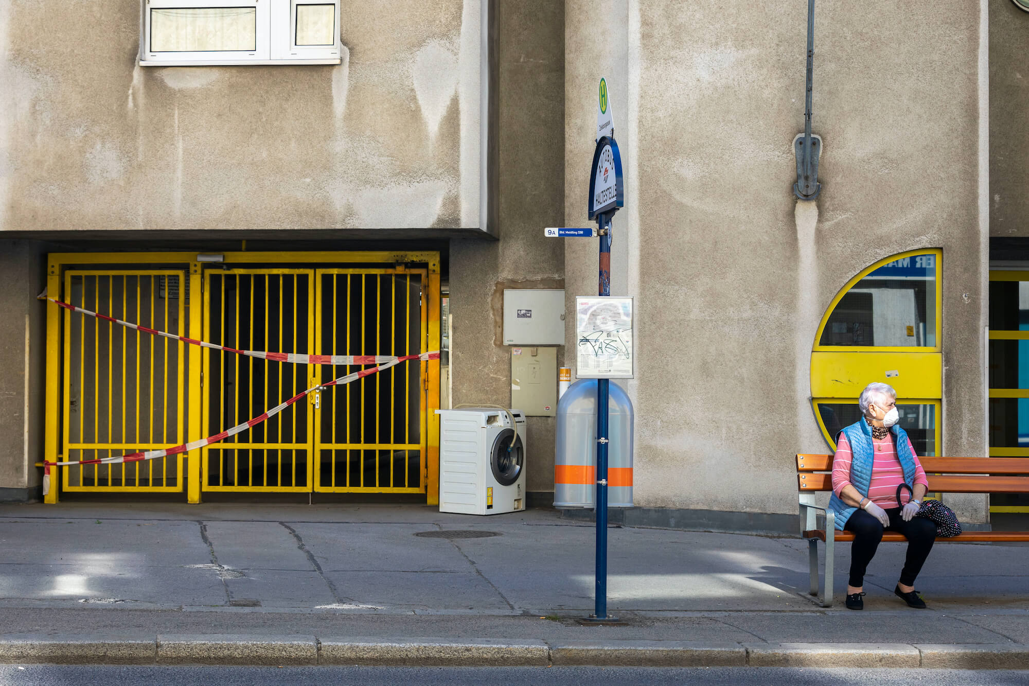 Frau trägt Maske und wartet in Wien auf ihren Bus.