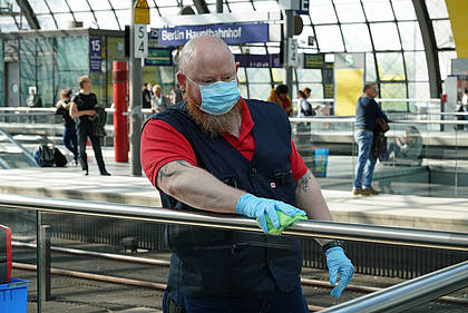 DB Mitarbeiter reinigt Handlauf im Bahnhof.