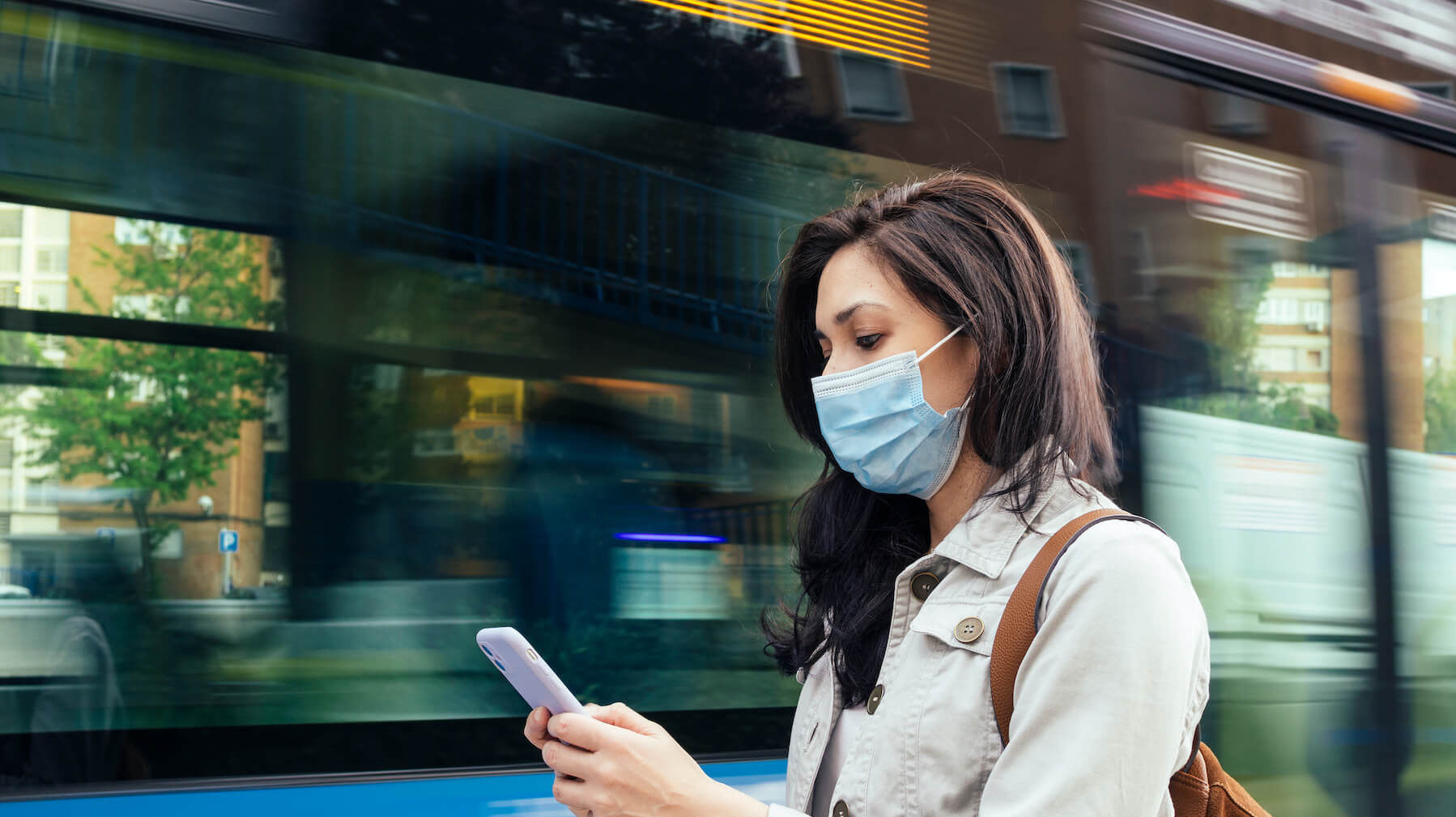 Frau steht mit medizinischer Maske vor einem Bus