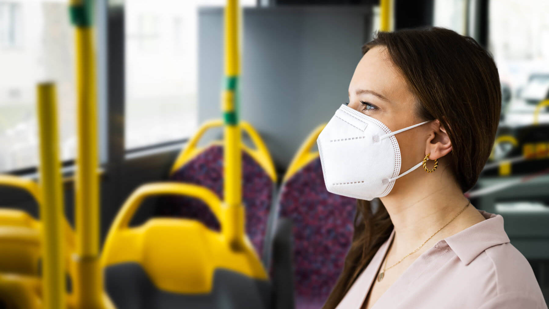 Frau steht im Bus und trägt eine FFP2-Maske