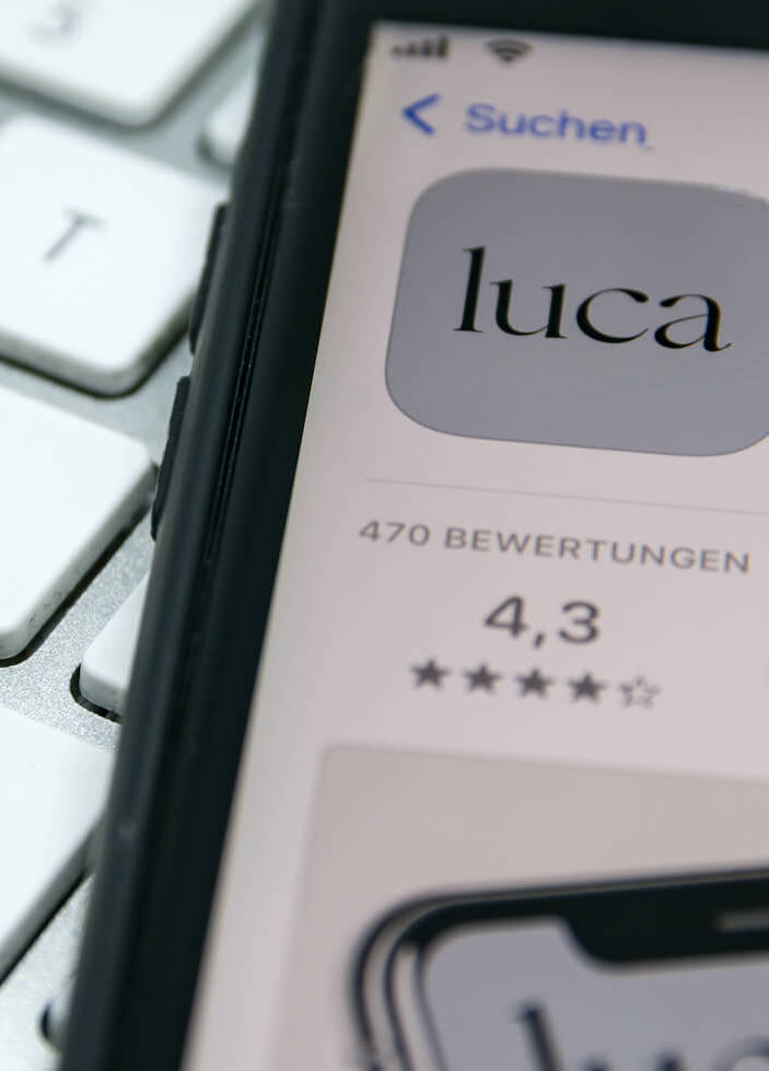 Smartphone, auf dem die App luca zum Download bereit steht