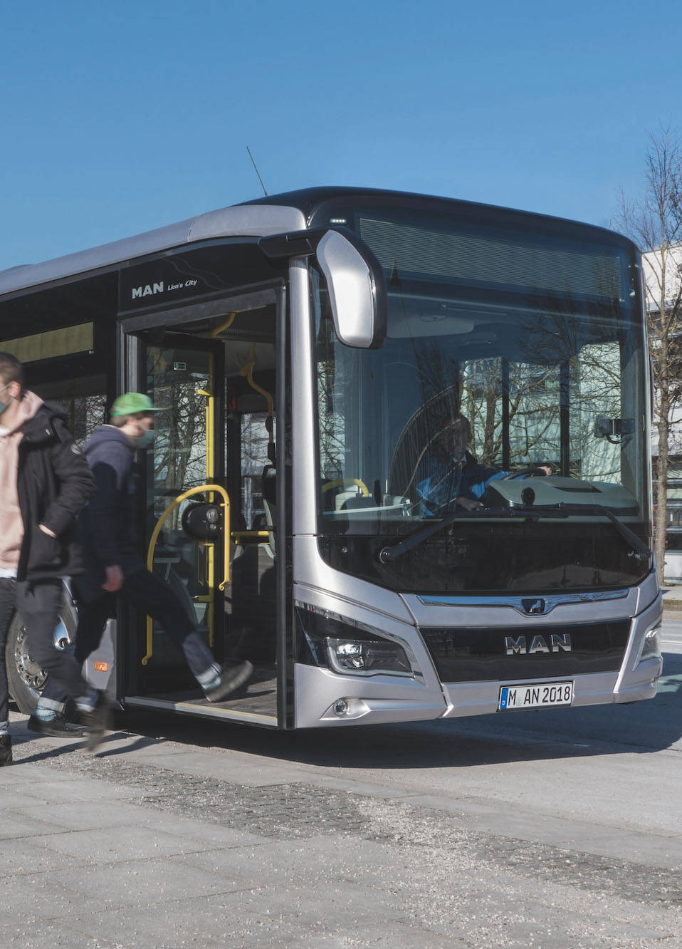 Menschen mit Masken steigen an einer Haltestelle aus einem Bus