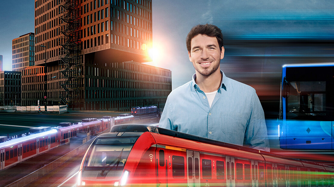 Zu sehen ist Felix Neureuther der ein blaues Hemd trägt, eine rote S-Bahn und eine moderne Stadt im Hintergrund.