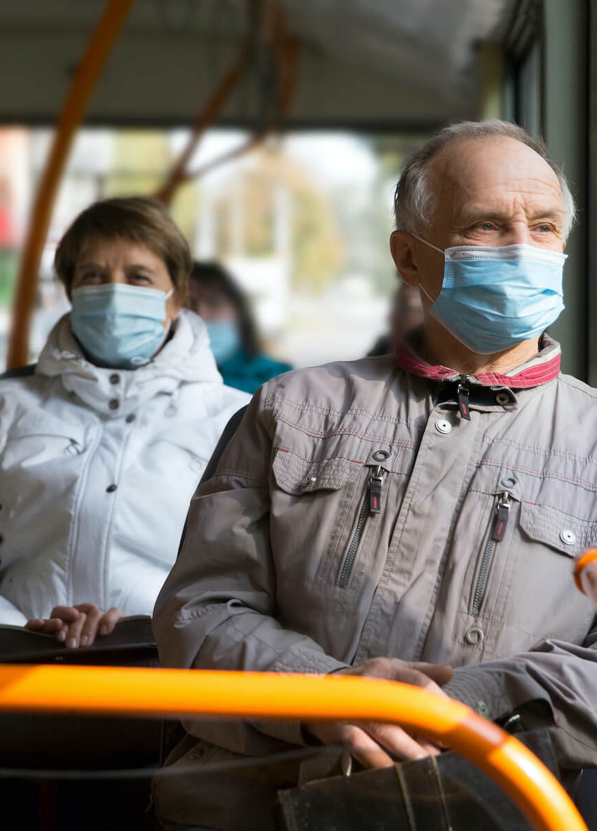Menschen sitzen mit medizinischer Maske im Bus