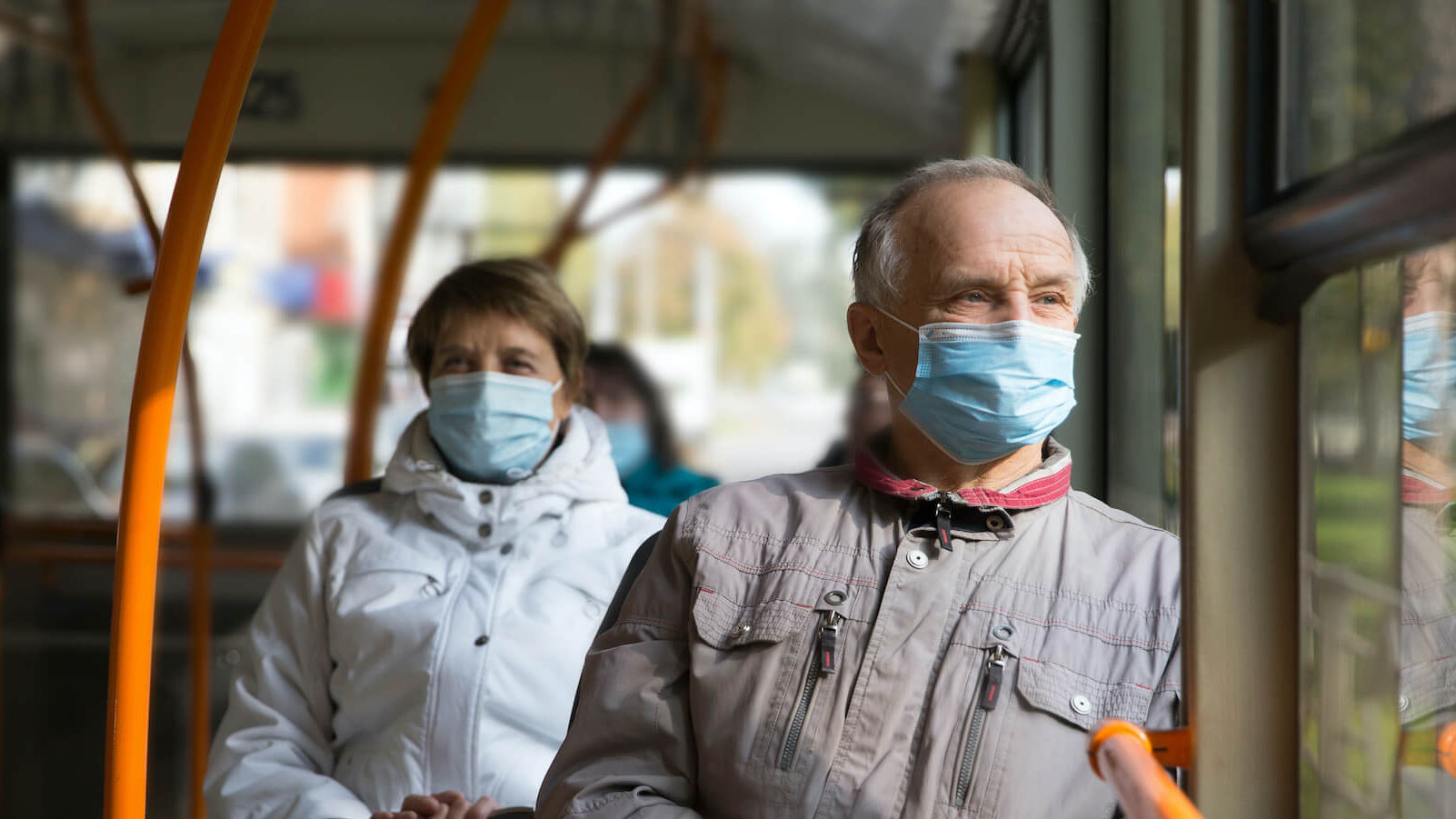 Menschen sitzen mit medizinischer Maske im Bus