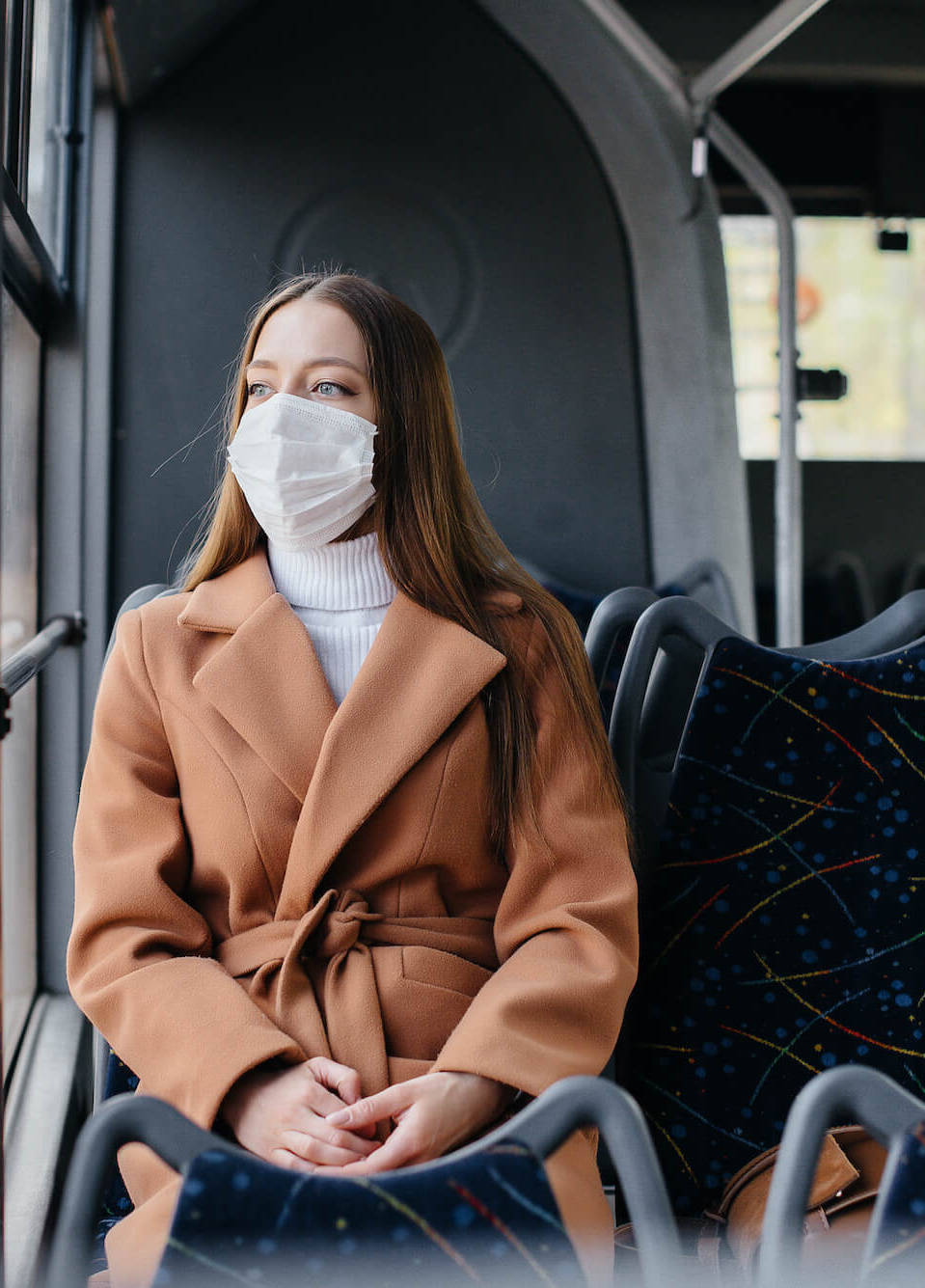 Frau mit Maske sitzt im Bus
