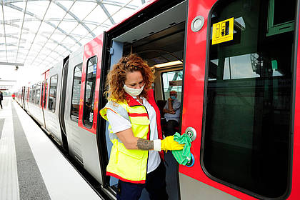 Mitarbeiterin des Hochbahn-Hygieneteams reinigt Druckknöpfe einer Bahn.