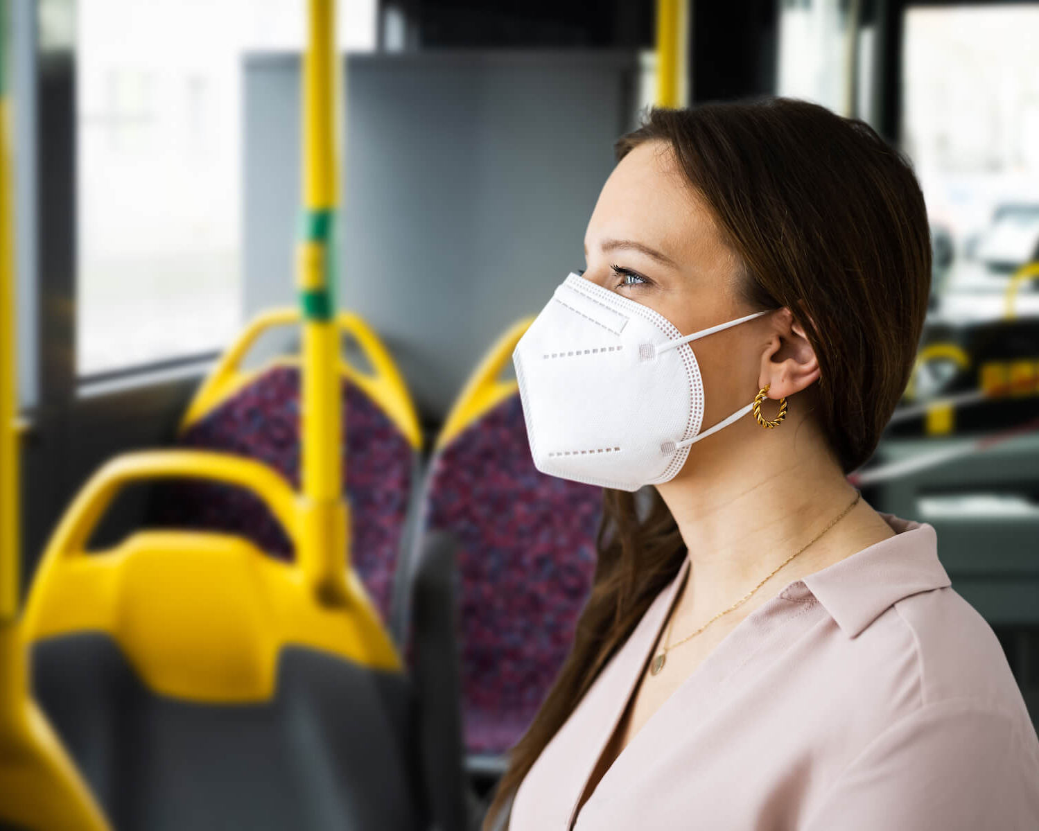 Frau mit FFP2-Maske steht im Bus