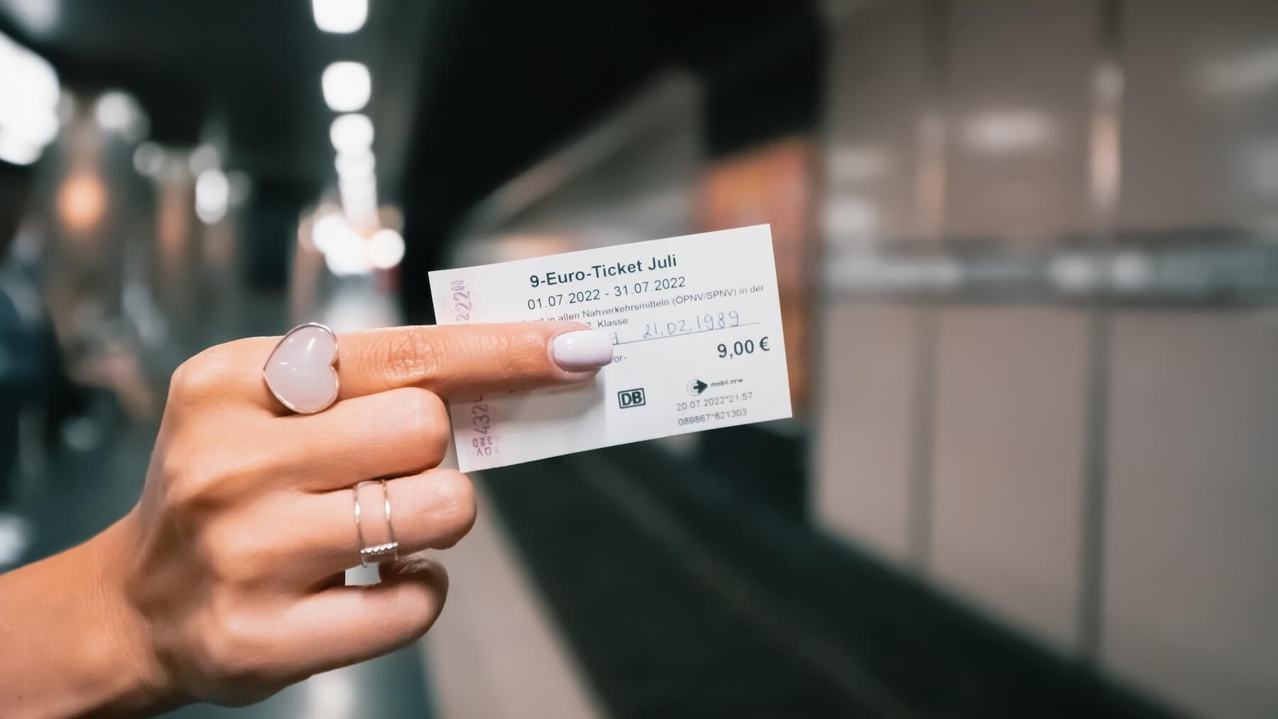 Frau hält das 9-Euro-Ticket hoch.