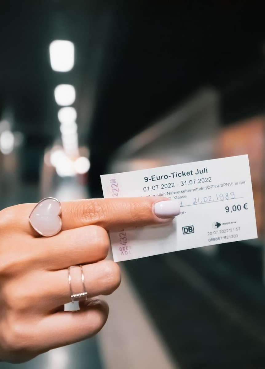 Frau hält das 9-Euro-Ticket hoch.