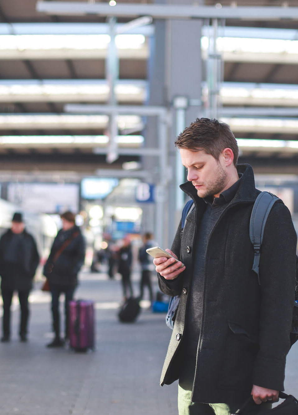 Mann schaut am Bahngleis auf sein Handy