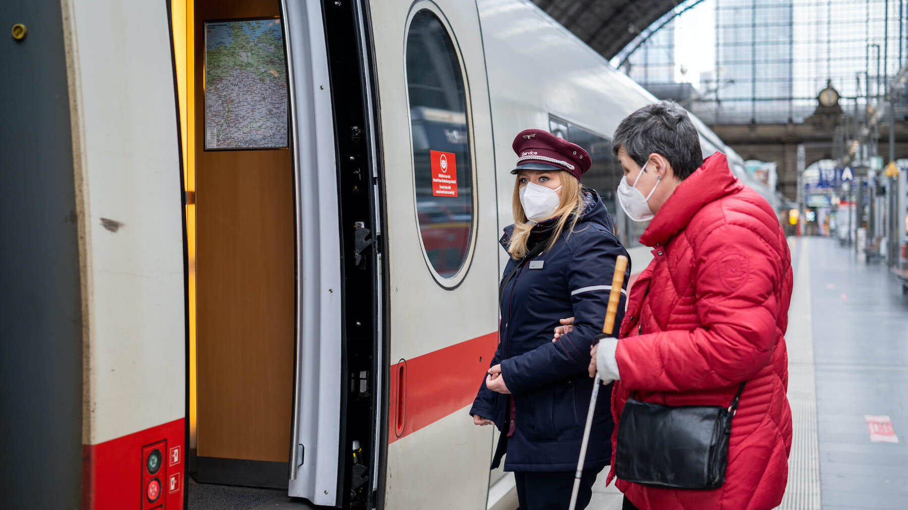 DB-Mitarbeiterin hilft einer Kundin beim Einstieg in einen ICE