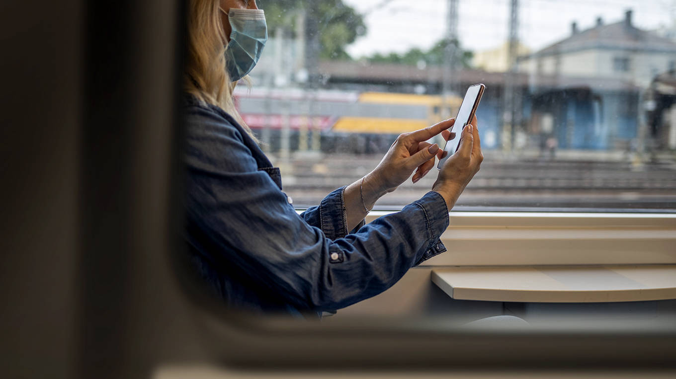 Frau sitzt mit Smartphone in der Bahn.