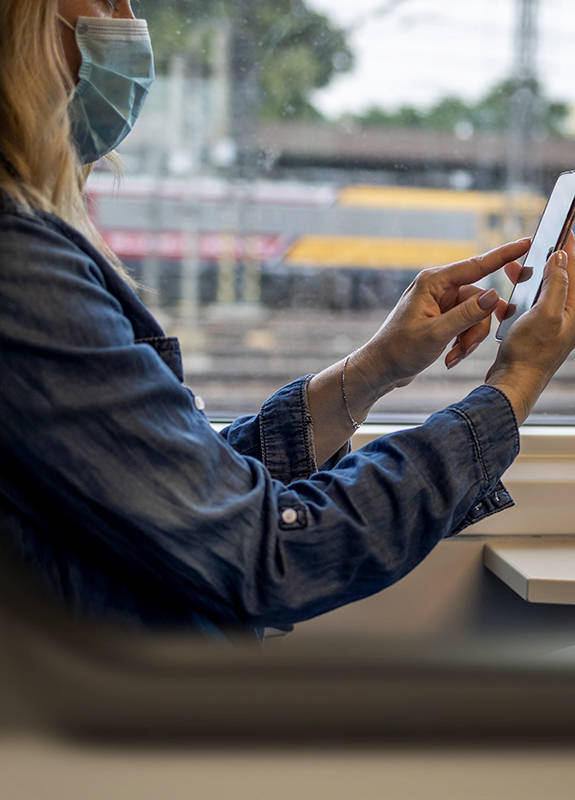 Frau sitzt mit Smartphone in der Bahn.