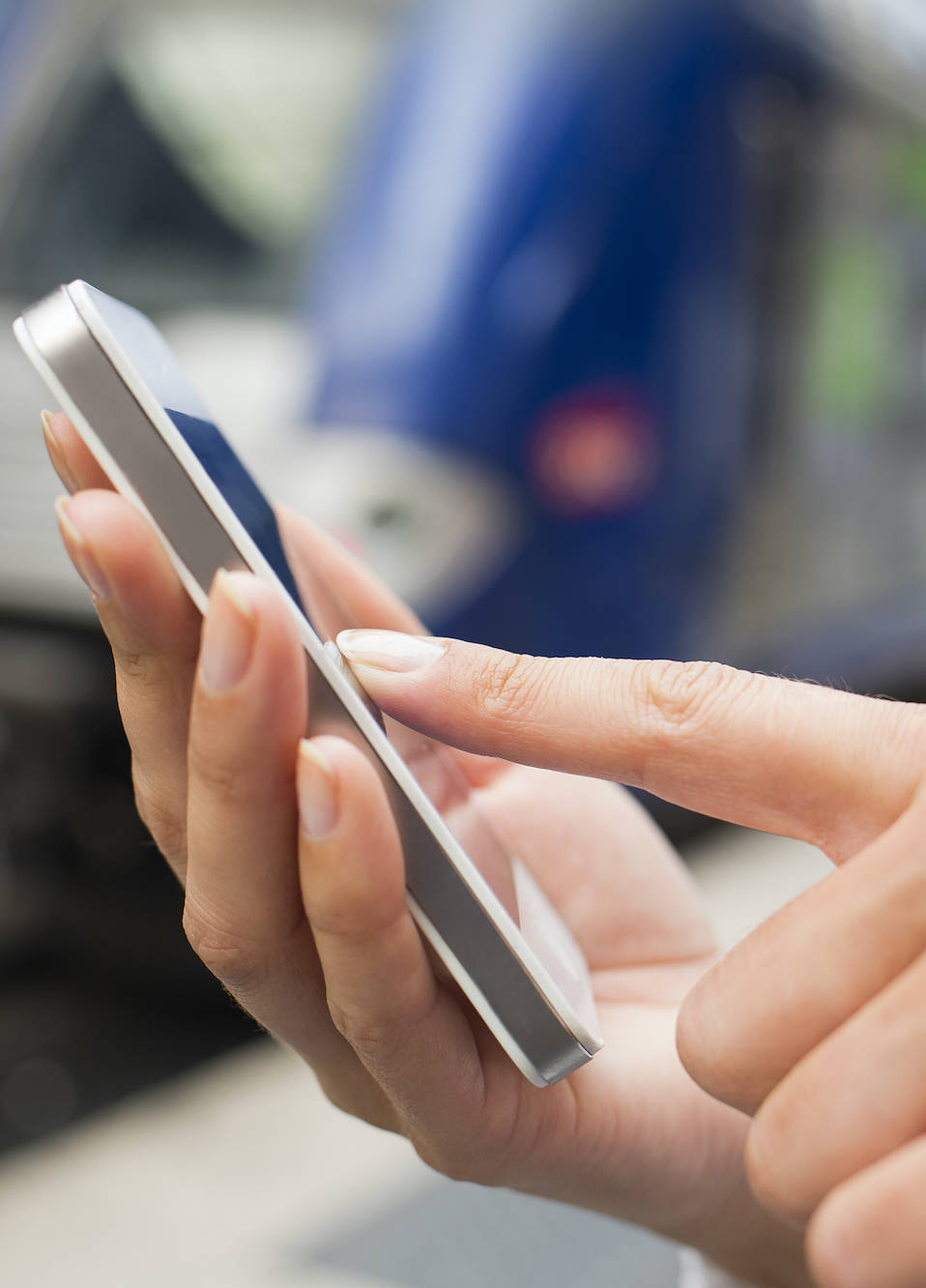 Frau bedient ihr Smartphone am Bahngleis