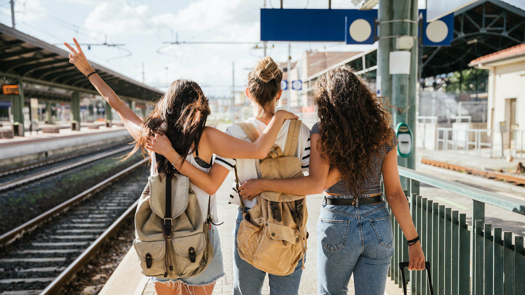 Eine Gruppe von Mädchen stehen mit Koffer am Bahngleis